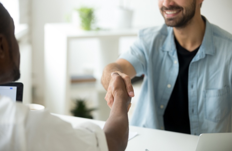 Young diverse multiracial businessmen shaking hands, african american and caucasian entrepreneurs binding contract deal with handshake establishing multi-ethnic partnership concept, close up view